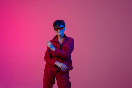 Mature european woman wearing sunglasses dancing on camera isolated over pink backgroundの写真素材
