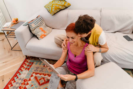 Mature lesbian couple using tablet computer while resting together at homeの写真素材