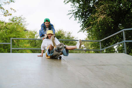 Multiracial friends making fun while riding in skate park on summer day