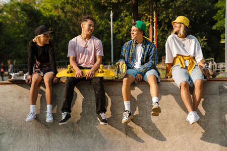 Multiracial teenagers talking and laughing while spending time at skate park outdoors