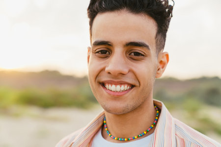 Young middle eastern man smiling during walking on summer beachの写真素材