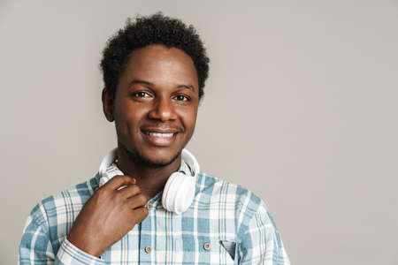 Black man smiling while posing with headphones isolated over white backgroundの写真素材