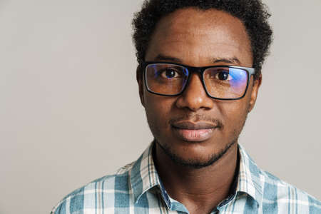 Young black man wearing eyeglasses posing and looking at camera isolated over white background