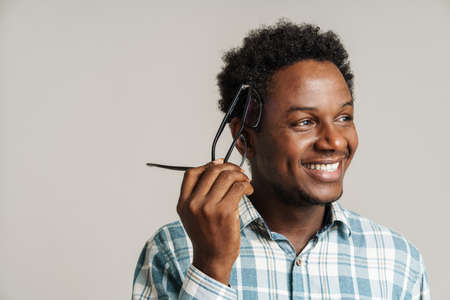Young black man wearing eyeglasses smiling and looking aside isolated over white backgroundの写真素材