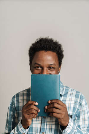 Black unshaven man in plaid shirt posing with exercise book isolated over white backgroundの写真素材