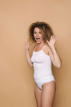 Young blonde woman wearing underwear expressing surprise at camera isolated over beige backgroundの写真素材