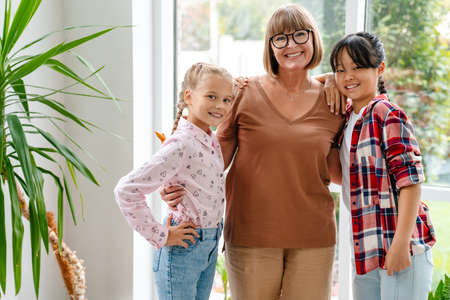 White mature teacher smiling while hugging her students indoors