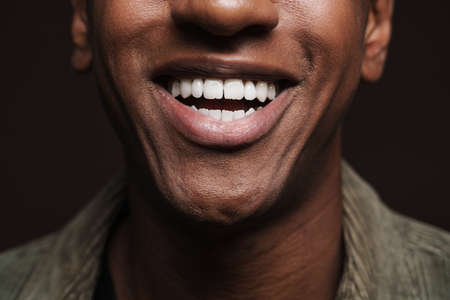 Young black man dressed in shirt smiling and looking aside isolated over brown wallの写真素材