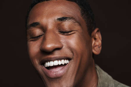 Young black man laughing with his eyes closed isolated over brown wallの写真素材