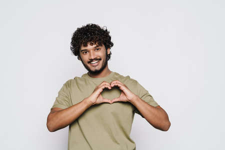 Young bearded man smiling and showing heart gesture isolated over white background
