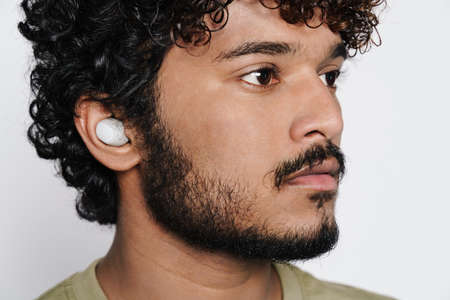 Young middle eastern man listening music with earphones isolated over white wallの写真素材