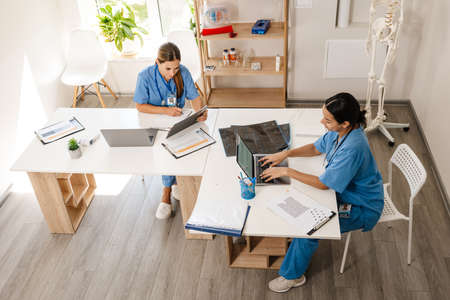 Multiracial women doctors working with laptops in office indoors