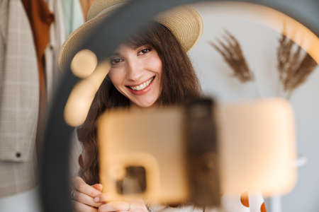 White woman smiling while taking selfie footage on cellphone at homeの写真素材