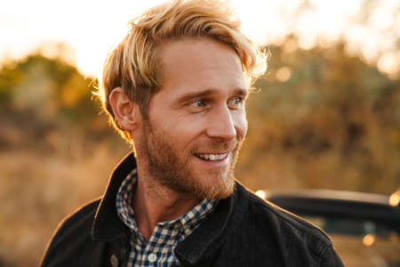 White bearded man smiling while standing by car outdoors