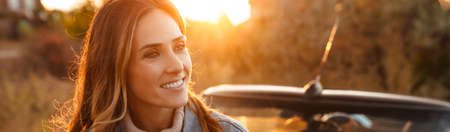 White ginger woman smiling while standing by car outdoors