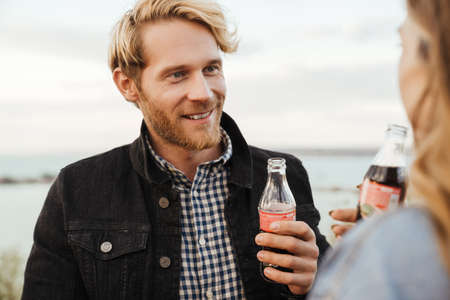 White mid couple drinking soda and talking while standing outdoors