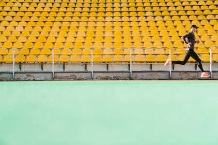 Young white sportsman running while working out on stadium outdoorsの写真素材