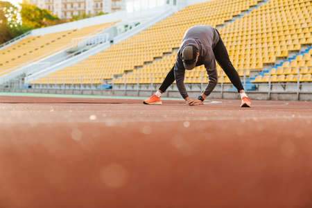 Young sportsman doing exercise while working out at stadium outdoorsの写真素材