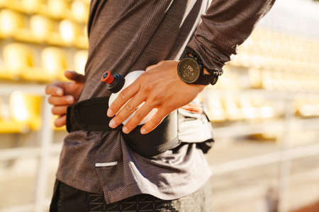 Young white sportsman drinking water while working out on stadium outdoorsの写真素材