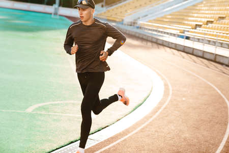 Young white sportsman running while working out on stadium outdoorsの写真素材