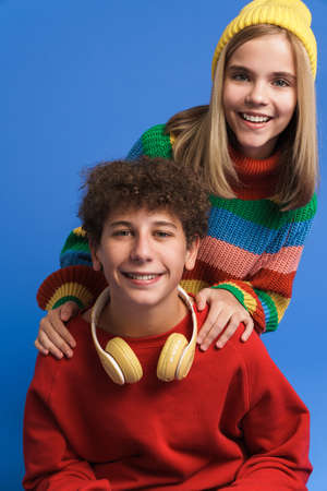 White girl and boy laughing and hugging while posing at camera isolated over blue backgroundの写真素材