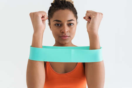 Black young sportswoman working out with expander stretch tape isolated over white backgroundの写真素材