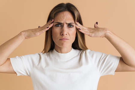 White mid woman rubbing her temples and looking upward isolated over beige background