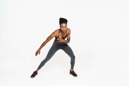Young black sportswoman doing exercise while working out isolated over white background