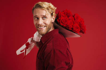 White bearded man smiling while posing with roses isolated over red wallの写真素材