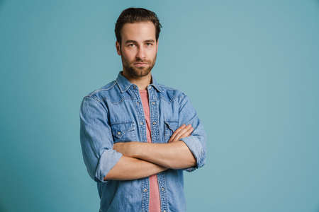 Young bristle man wearing shirt posing with arms crossed isolated over blue backgroundの写真素材