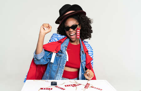 Young black woman making winner gesture while posing with shopping isolated over white background