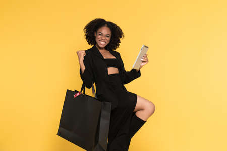 Black woman using tablet computer while making winner gesture isolated over yellow backgroundの写真素材