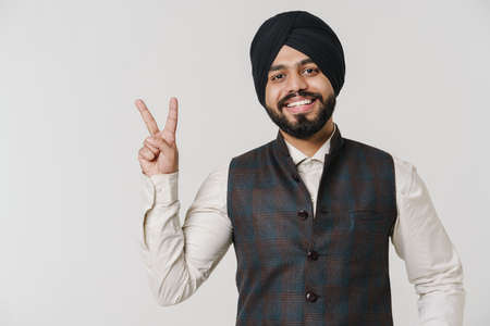 Bearded south asian man wearing turban smiling and gesturing isolated over white wallの写真素材