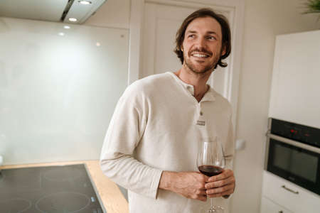 European unshaven man using laptop while resting on sofa at homeの写真素材
