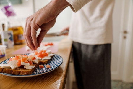 European man making sandwich with cheese in kitchen at homeの写真素材