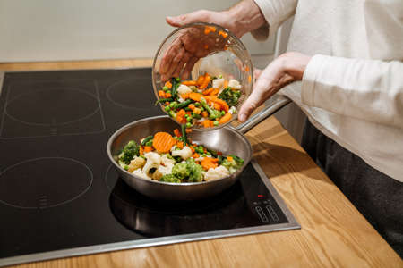 European man making dinner with vegetables in kitchen at homeの写真素材