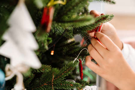 Photo of white girl's hands decorating christmas tree at homeの写真素材