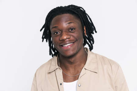 Young black man with dreadlocks smiling and looking at camera isolated over white backgroundの写真素材