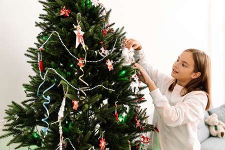 White blonde girl decorating christmas tree at homeの写真素材