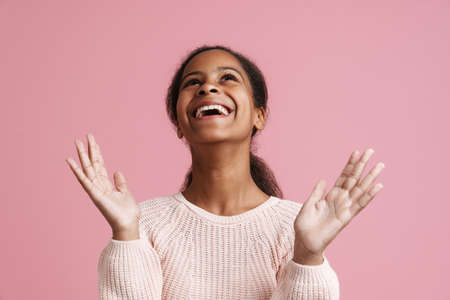 Brunette black girl gesturing while laughing at camera isolated over pink backgroundの写真素材