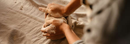 Young black ceramist woman wearing apron sculpting in clay at her workshopの写真素材