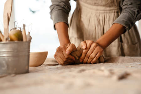 Young black ceramist woman wearing apron sculpting in clay at her workshopの写真素材