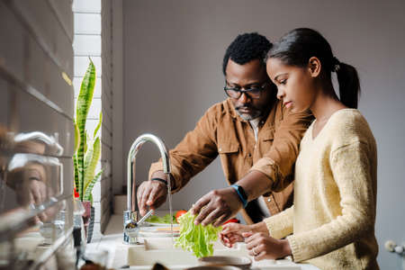 Black bearded man making sandwiches with his daughter at homeの写真素材