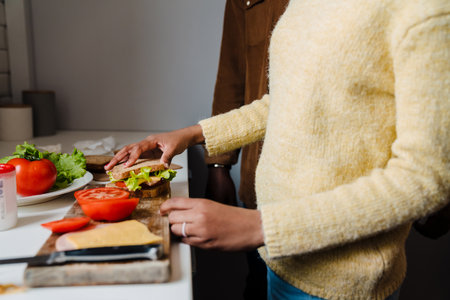 Black bearded man making sandwiches with his daughter at homeの写真素材