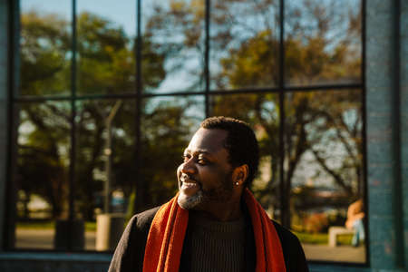 Black bearded man smiling while standing on city street outdoorsの写真素材