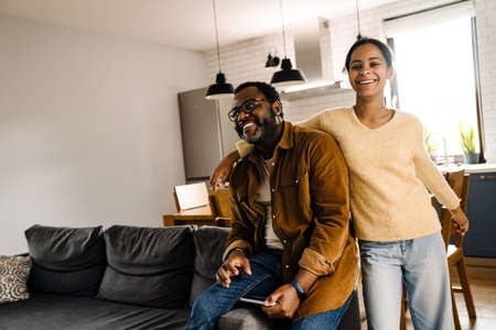 Black girl and her father laughing and using cellphone at homeの写真素材