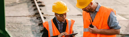 Multiracial man and woman wearing helmets working together in port