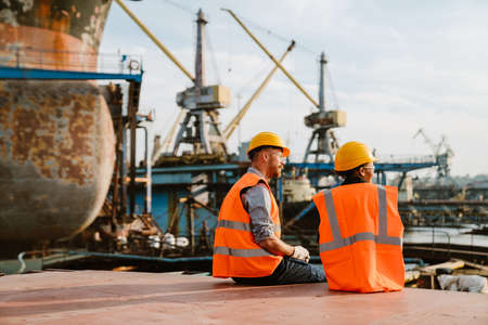 Multiracial man and woman wearing helmets working together at portの写真素材