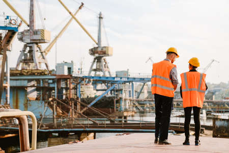 Multiracial man and woman in protective clothing working together at portの写真素材