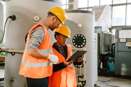 Multiracial man and woman in protective clothing working together at factoryの写真素材